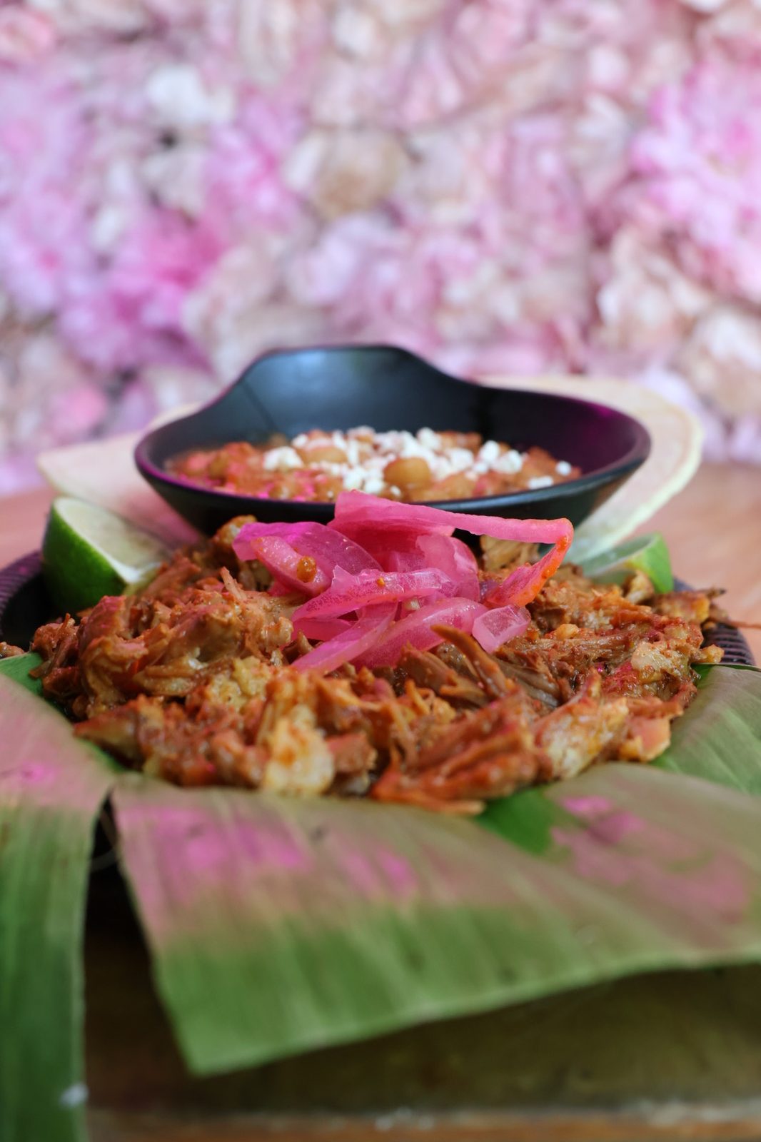 Cochinita Pibil slow-smoked pulled pork on banana leaf with pickled red onion, rice and beans