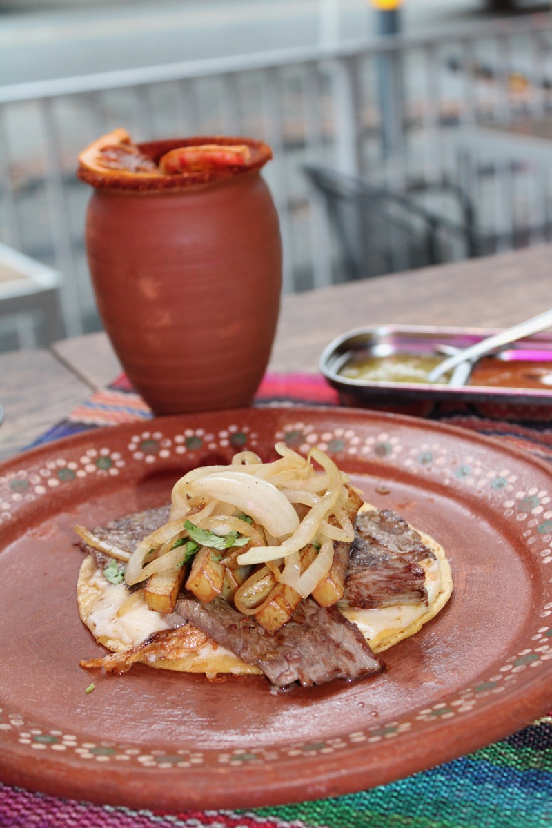 Taco Norteño with grilled steak, crispy fries and caramelized onions on a clay plate