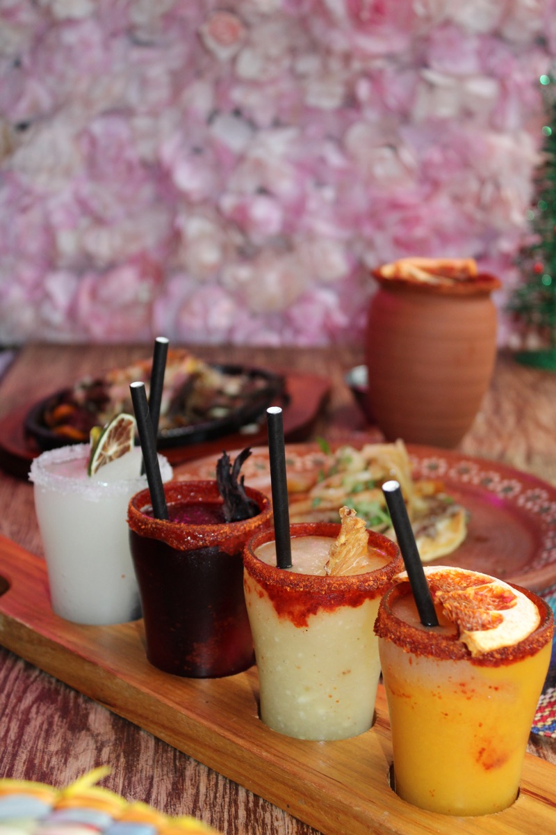 Frozen margarita flight of four flavours on a wooden board with chile rims